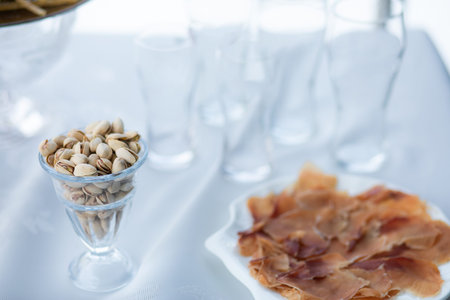 White glass of pistachios on table with empty beer glasses on background outdoor