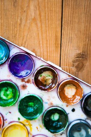 Set of multicolored watercolor paints on the wooden backgroundの写真素材