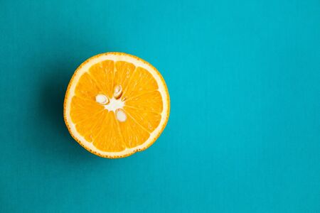 Half of orange on turquois background with copy space for your textの写真素材