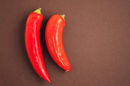 Set of two red chili peppers on the brown background