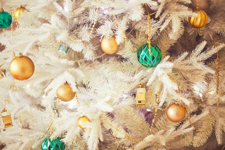 White Christmas tree branches with gold and green baubbles, close upの写真素材