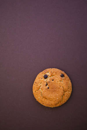 Round smiling cookie on the dark brown background with copy space for text. Oatmealの写真素材