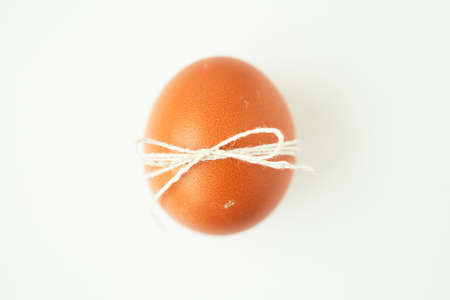 Brown egg wrapped with thread on white background with copy space.の写真素材