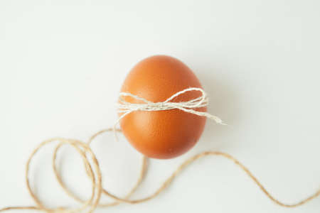 Brown egg wrapped with thread on white background.の写真素材
