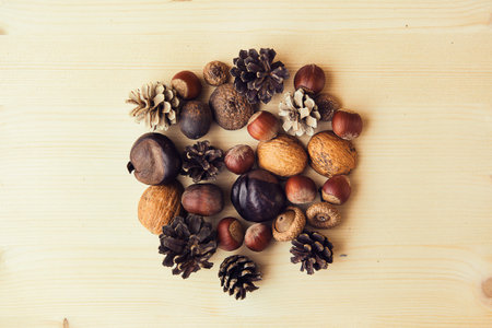 Autumn composition with nuts, chestnuts, wallut shells and pine cones on wooden background, flat lay, top view, copy space.の写真素材