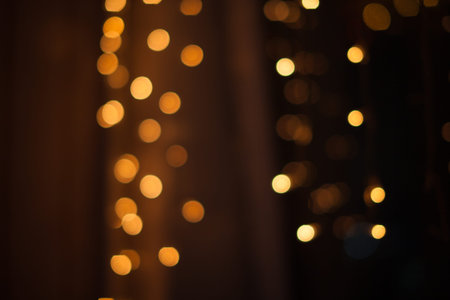 Abstract bokeh lights. Defocused shining yellow light leaks on dark background. New year, christmas garlands flecksの写真素材