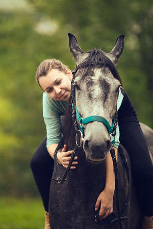 Young girl sits astride a gray horseの写真素材