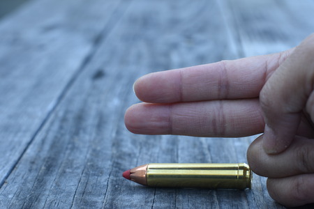 Red tip 450 Caliber ammunition and finger on wooden backgroundの写真素材