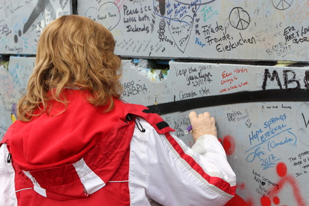 February 20 2018, Belfast Northern Ireland: Editorial photograph of a women signing the peace wall that is situated in Belfast. The peace wall is a symbol of peace between the loyalists and British.のeditorial素材