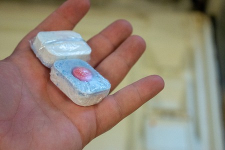 Woman putting tablet in dishwasher detergent box.の写真素材