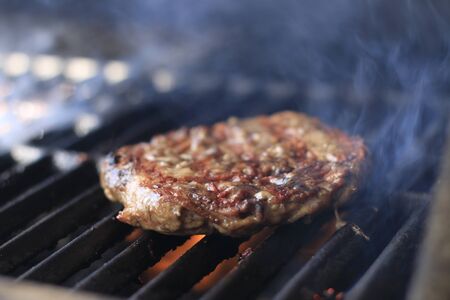 Burgers. Hamburgers being flame broiled on the gas grillの写真素材