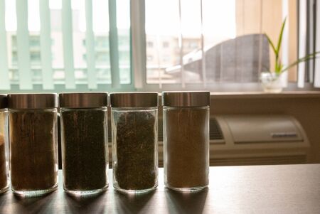 Assortments of spices, white pepper, chili flakes, lemongrass, coriander and cumin seeds in jars on grey stone backgroundの写真素材