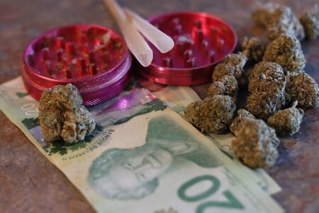 A grinder, pre rolled joints, canadian money, and weed.の写真素材