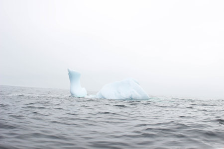 Wave crashing against small iceberg bit floating in sea