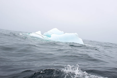 Wave crashing against small iceberg bit floating in sea