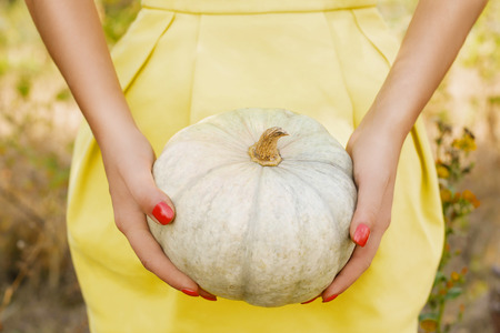 Girl in yellow dress holding little pumpkinの写真素材