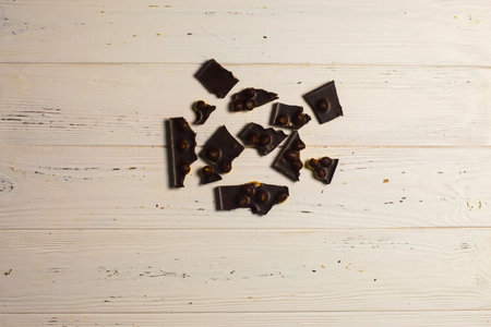 Pieces of nut chocolate on wooden background