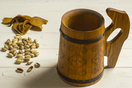 Wooden Beer Mug, Pistachio Nuts, and Dried Bread on Wooden Backgroundの写真素材