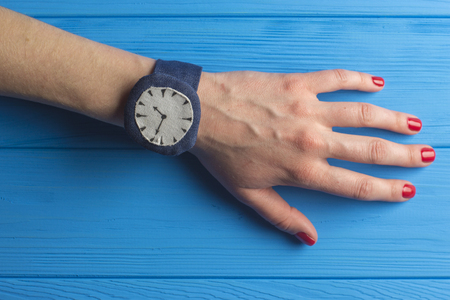 Female Hand with Watch on Blue Wooden Backgroundの写真素材
