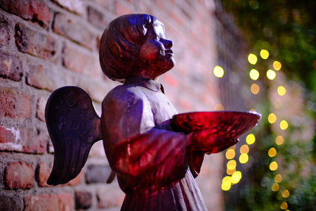 Bronze statue of an Angel in front of christmas illumination, at the chapel