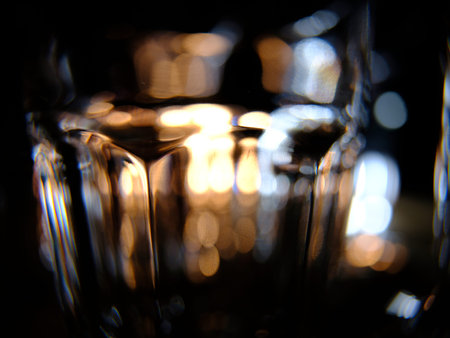 Close ups of wine-, long drink- and spirits-glasses on a wooden shelve in a bar, in front of a dark...