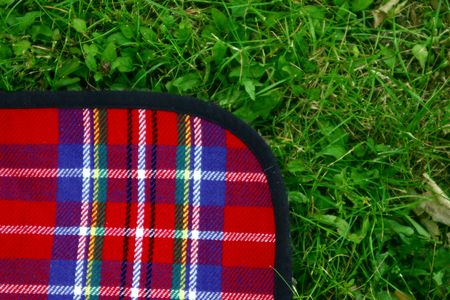 A red squared tablecloth is on the green grass waiting for the launch or breakfast timeの写真素材