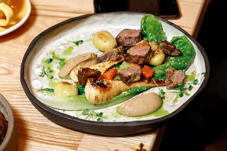 meat on a plate with potatoes and radish, laid out on a lettuce leaf with the addition of...