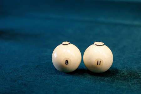 two white balls for billiards with gold rings on them against the background of the green cloth of the billiard tableの写真素材
