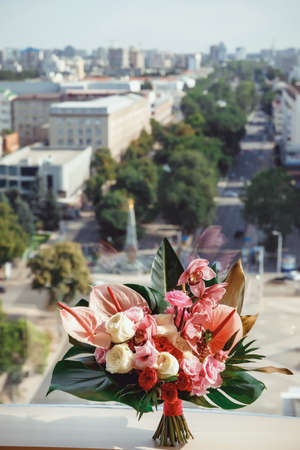 bridal bouquet of tropical flowers on the window against the background of the city panoramaの写真素材