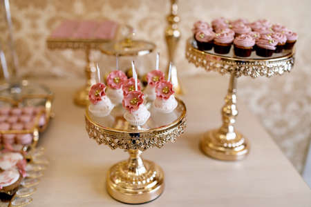 pink candies and cupcakes at a candy bar, decorated with pink caramel flowers and pastry beadsの写真素材