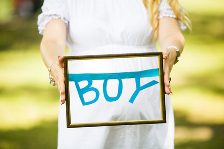 pregnant woman holding the inscription boy