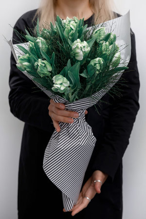 Girl in a black dress holds a bouquet of roses on a white backgroundの写真素材