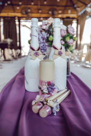 candles and champagne bottles decorated with white, pink and purple artificial flowers, ribbons, lace and fabricの写真素材