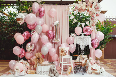 a white porcelain hare next to a brown wicker stroller, books in light pink wrapping paper, roses, orchids, balloons and a birdhouseの写真素材