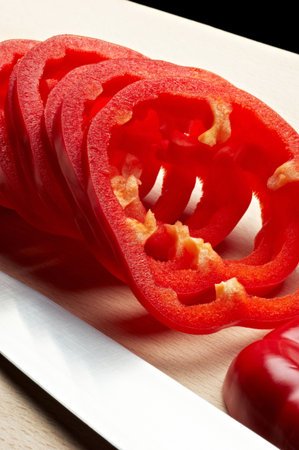 Sliced red pepper on cutting board with knifeの写真素材