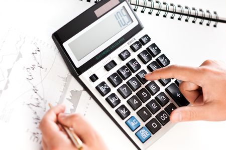 Close-up image of a businessman's hands calculating profit and analyzing stock chartsの写真素材