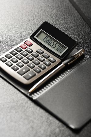 Close-up image of a calculator with a pen on a black backgroundの写真素材