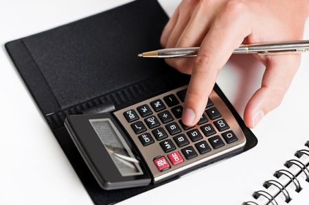 Close-up of a hand typing on calculator with a white backgroundの写真素材