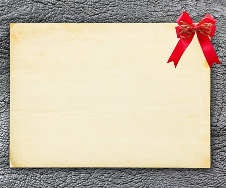 Vintage paper with red bow on leather backgroundの写真素材