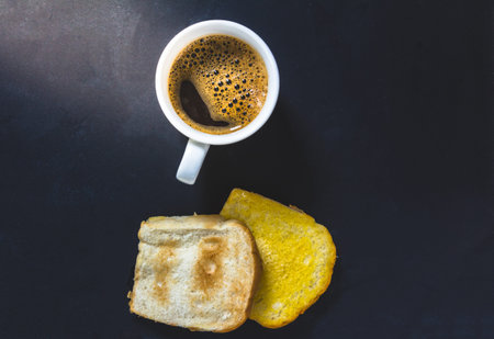 Cup of coffee with toast on black backgroundの写真素材