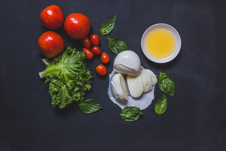 Homemade Organic Mozzarella Cheese with Tomato and Basil, top view on blackの写真素材