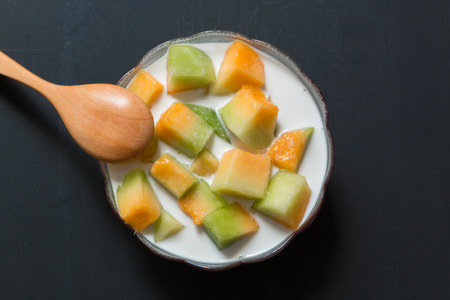 Thai style sweet dessert, Muskmelon eat with sweet coconut milk on black backgroundの写真素材