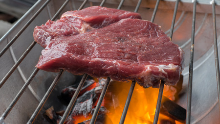 beef steak cooking over flaming grillの写真素材