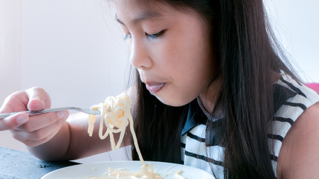 Asian child eating spaghettiの写真素材