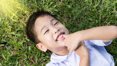 Portrait of smily Asain school boy laying on grassの写真素材