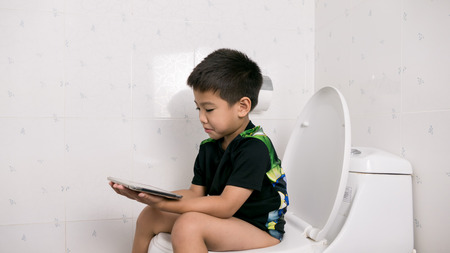 Asian boy playing tablet in restroomの写真素材