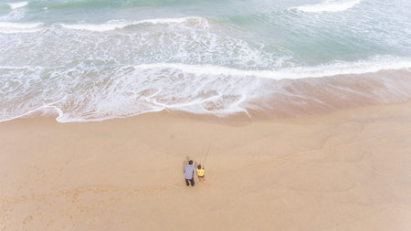 Aerial Father and son fishing in ocean surf in tropical beach in South of Thailand