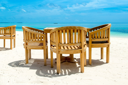 Wooden tables and chairs of tropical restaurant on the sandの写真素材
