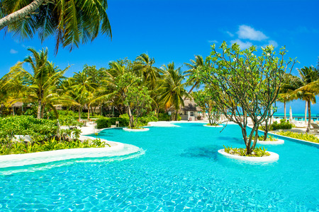 Lhaviyani Atoll, Maldives - 13 July 2018: Pool area on the shores of the Indian Ocean with sunbeds and umbrellas in the shade of the palm treesのeditorial素材