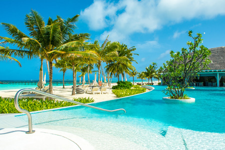 Lhaviyani Atoll, Maldives - 13 July 2018: Pool area on the shores of the Indian Ocean with sunbeds and umbrellas in the shade of the palm treesのeditorial素材